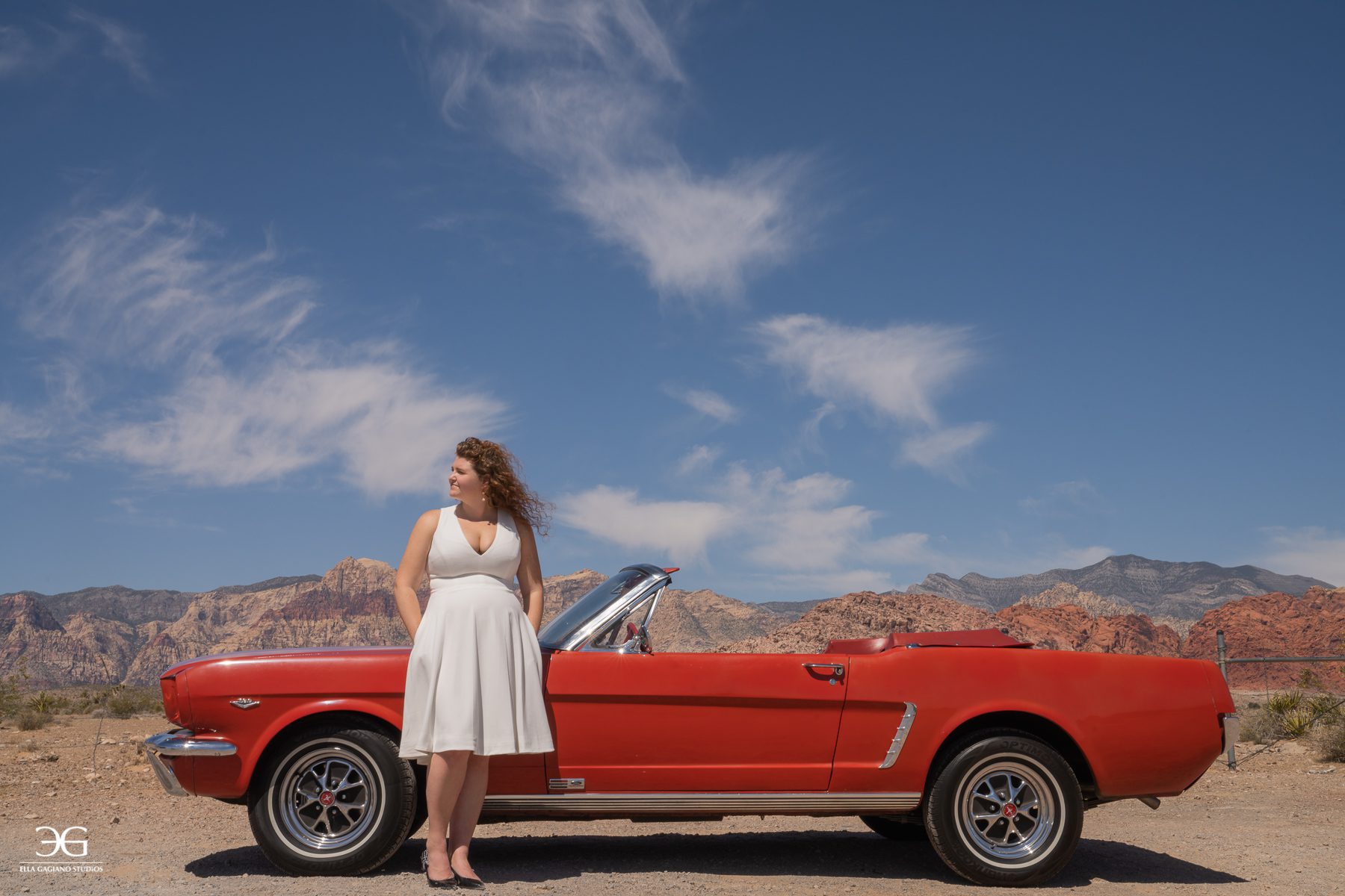 woman in white marilyn monroe dress in the desert with a red 1965 ford mustang
